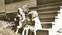 Photo of Edward Patrick Dunn on the steps of 10 Dayton Street with older brother Leo F. ('Sonny') Dunn and sisters Mary and Marget.